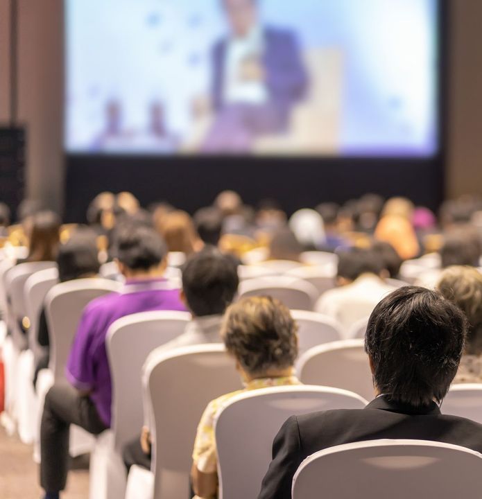 a group of people are sitting in chairs in front of a large screen .