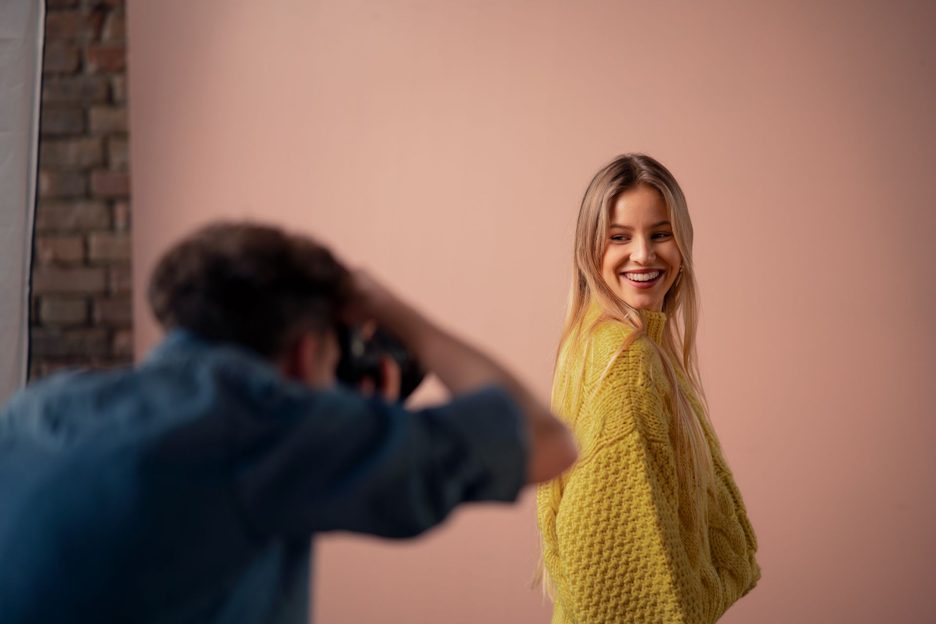 a man is taking a picture of a woman in a yellow sweater .