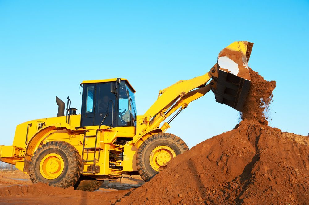 A Yellow Bulldozer is Loading Dirt Into a Pile — R.P's Total Assessments & Driver Training Pty Ltd In Tenterfield, NSW