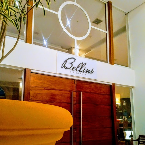Placa Bellini acima de uma entrada de madeira polida em um saguão interno com iluminação aconchegante.