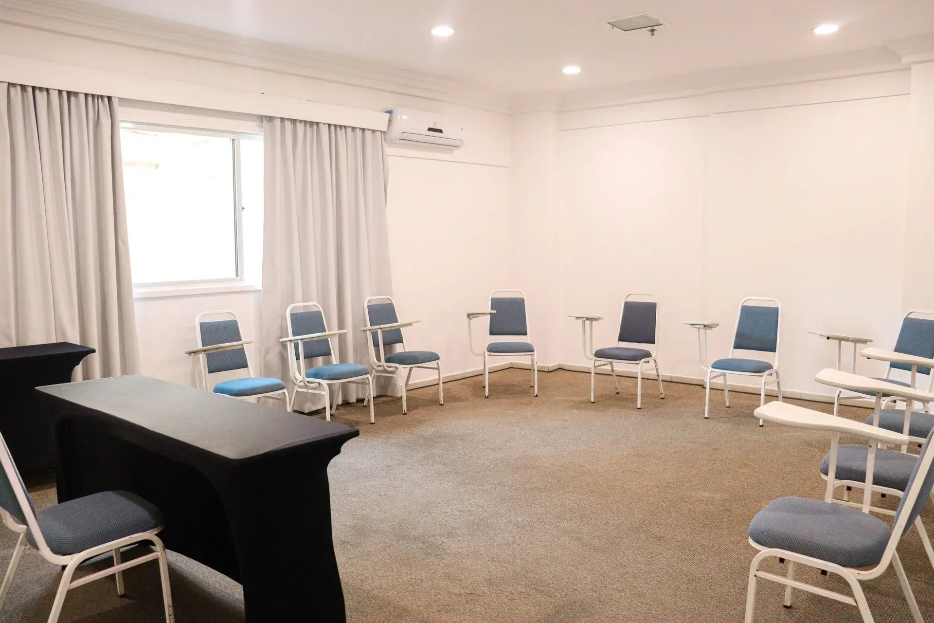 Uma sala com uma mesa e cadeiras dispostas em círculo.