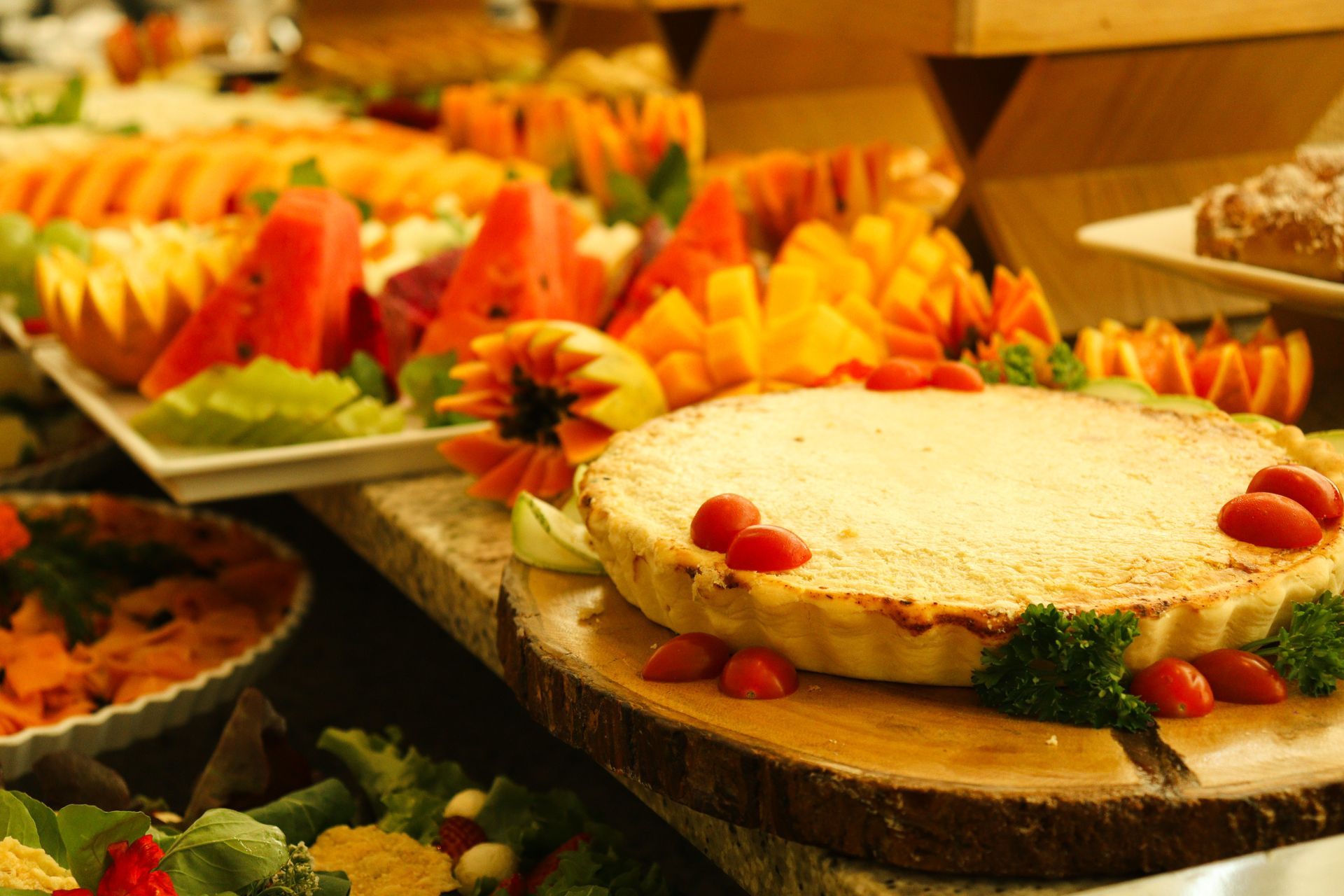 Uma torta com tomates por cima está sobre uma tábua de corte de madeira.