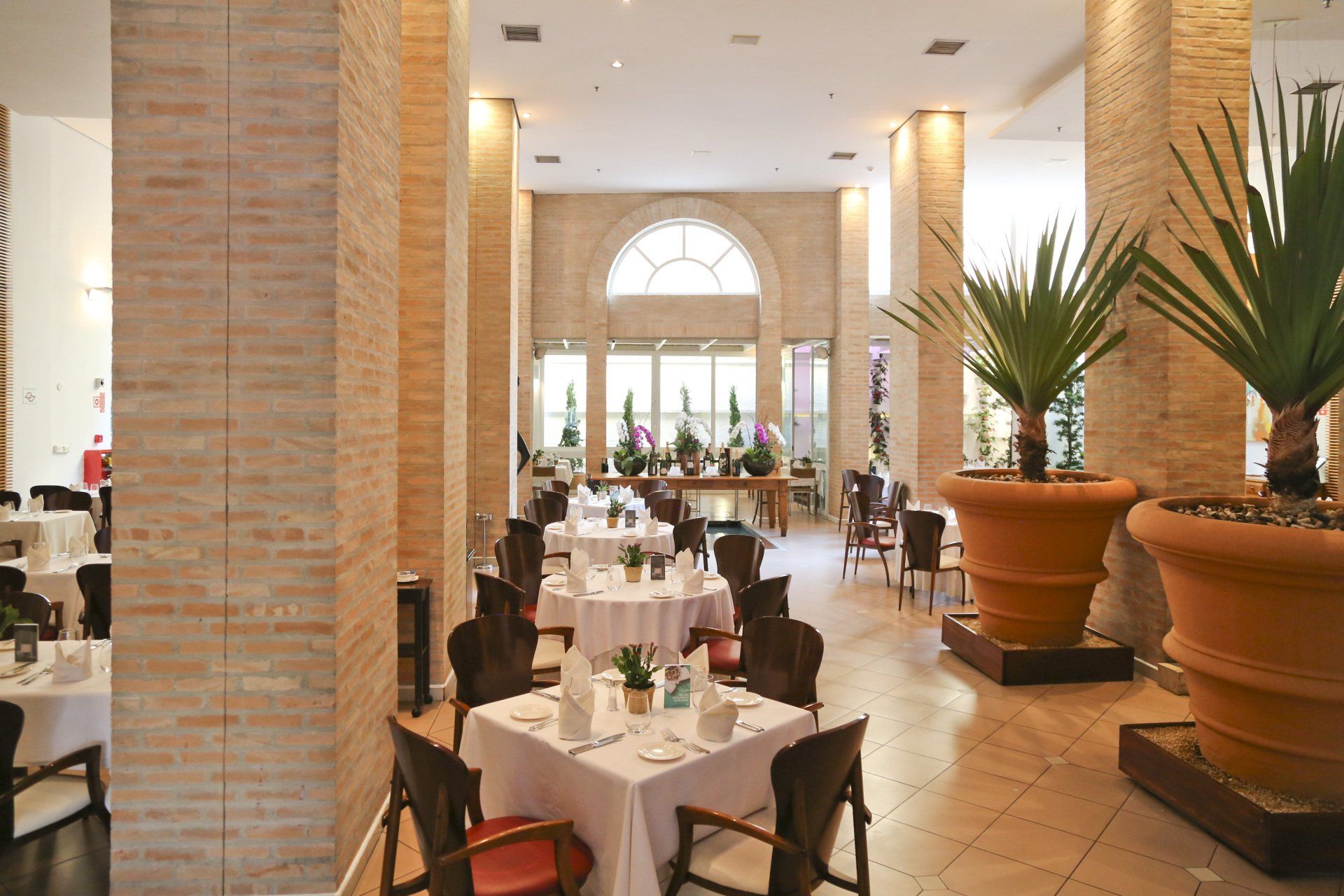 Um restaurante com mesas, cadeiras e plantas em vasos