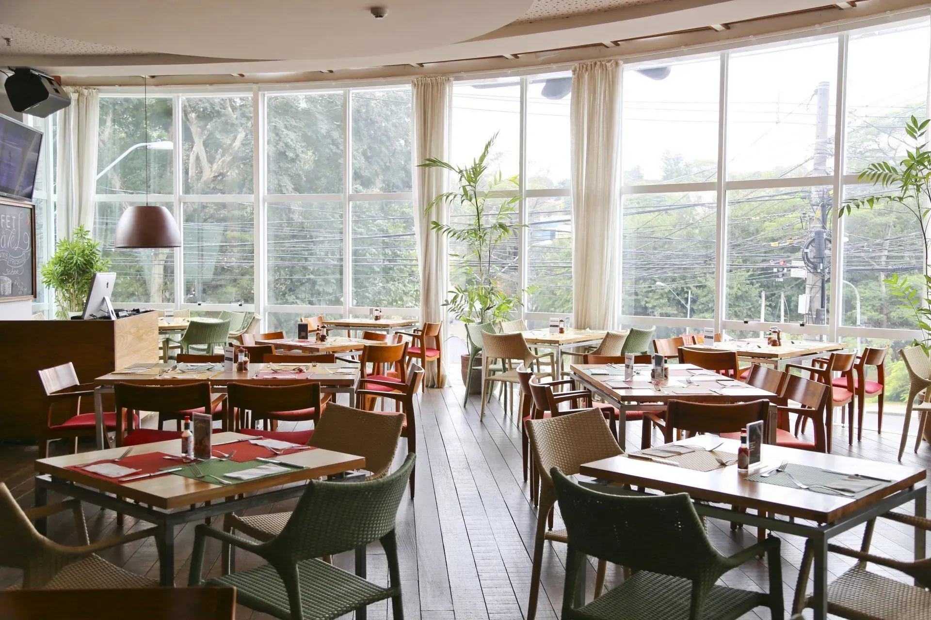 Um restaurante com mesas e cadeiras e muitas janelas.