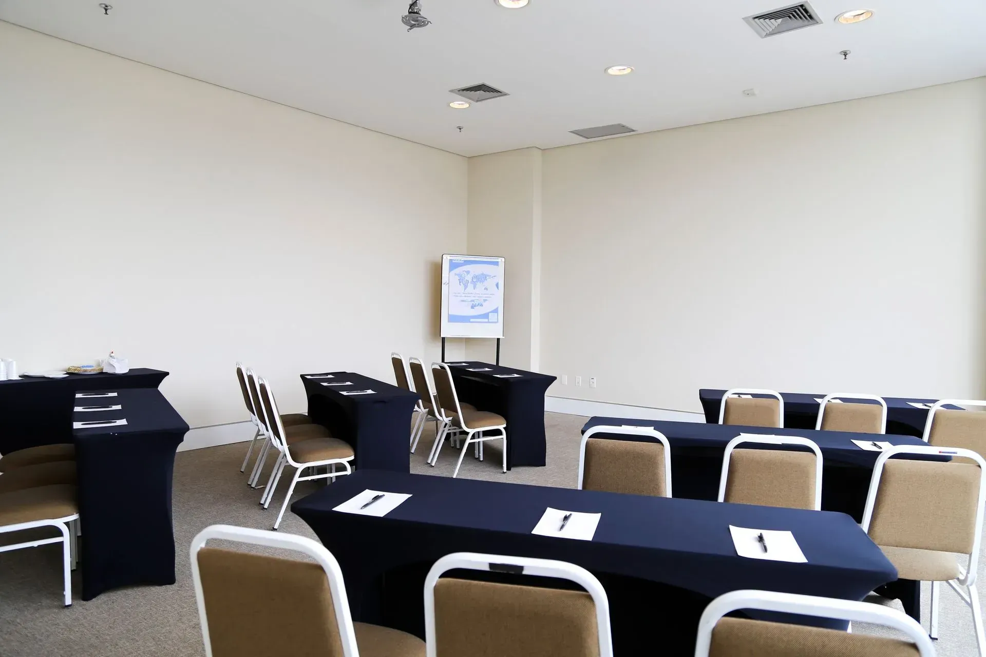 Uma sala de conferências com mesas e cadeiras preparadas para uma reunião