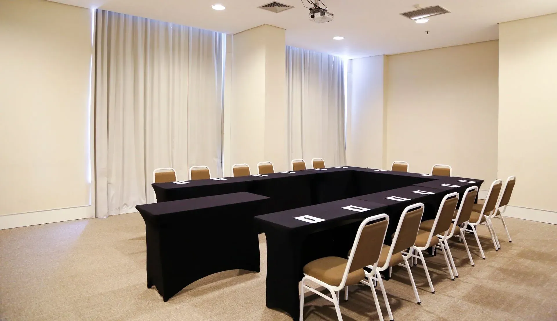 Uma sala de conferências com mesas e cadeiras preparadas para uma reunião.