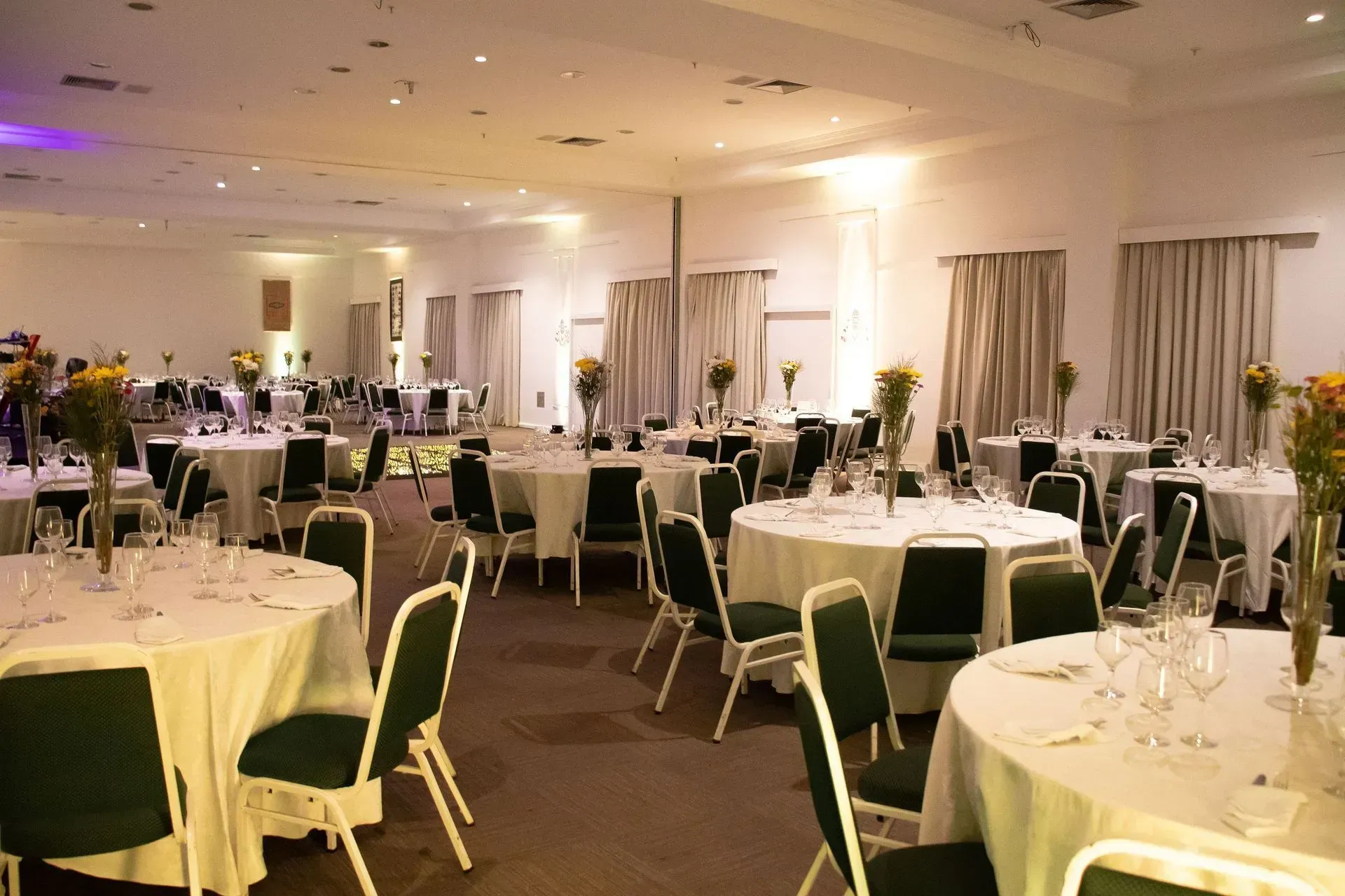 Uma sala grande com mesas e cadeiras preparadas para uma festa