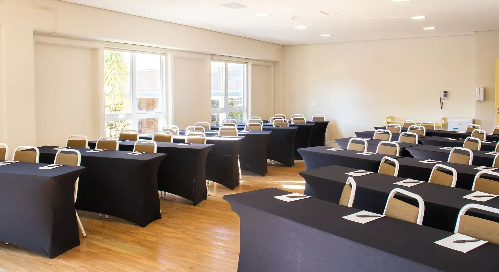 Uma sala de conferências com mesas e cadeiras preparadas para uma reunião.