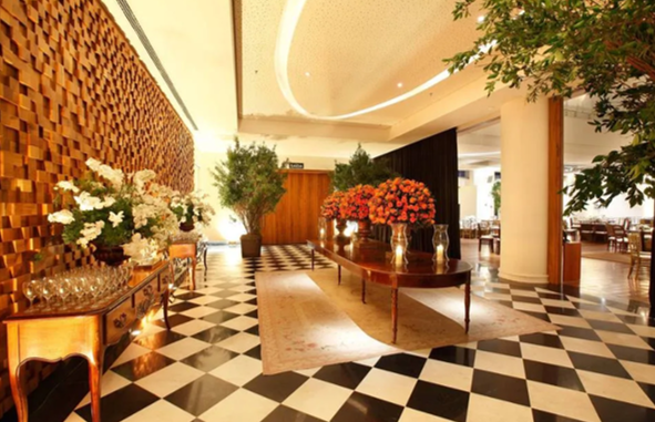 Hall de entrada elegante com piso xadrez preto e branco, arranjos florais e iluminação aconchegante.