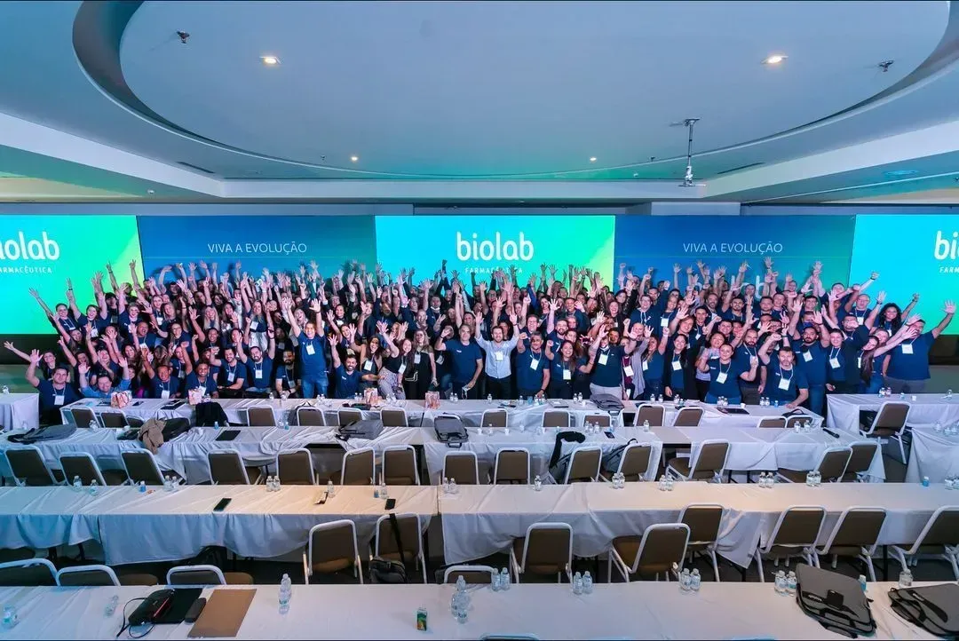 Um grande grupo de pessoas está posando para uma foto em uma sala de conferências.