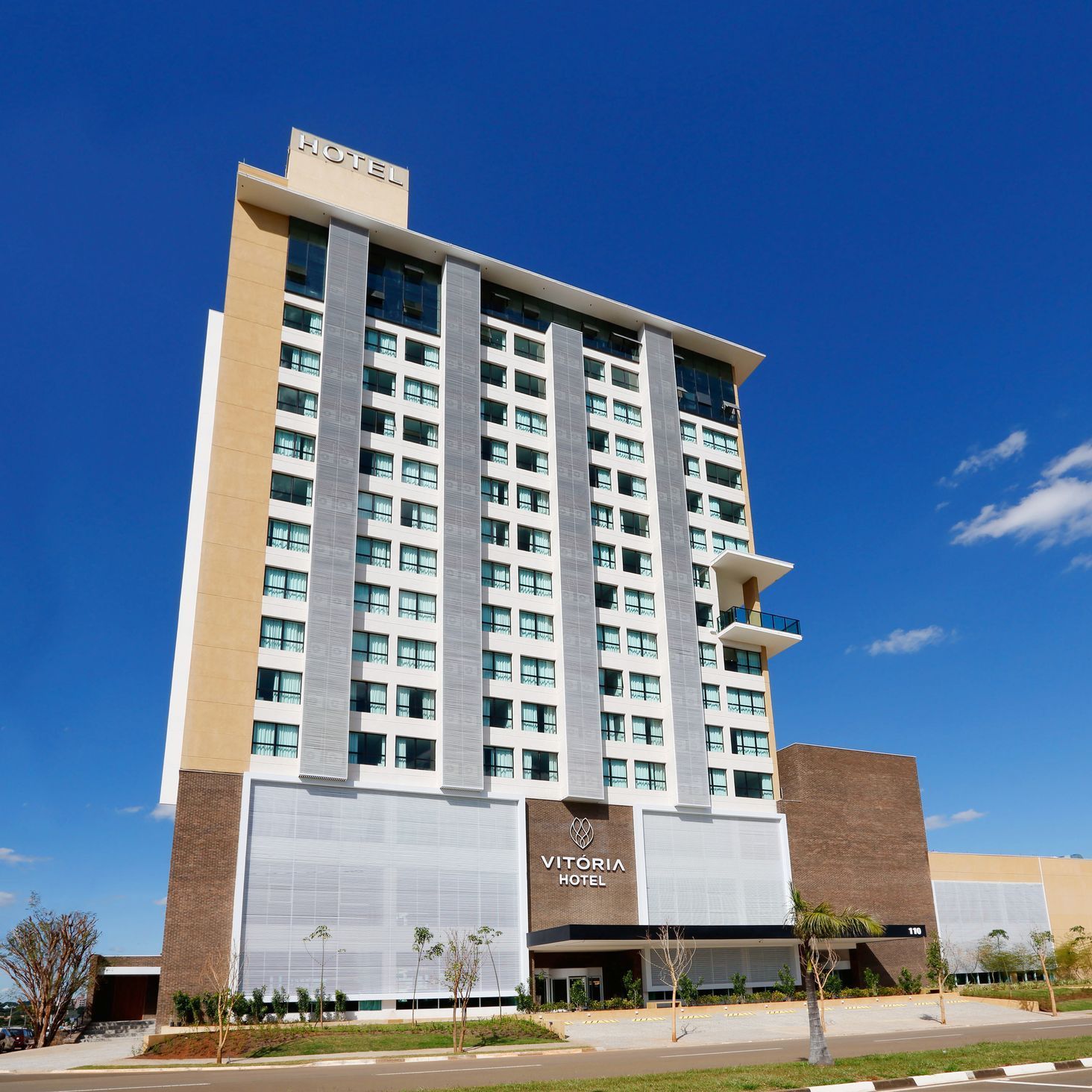 Edifício moderno de um hotel de vários andares sob um céu azul brilhante.