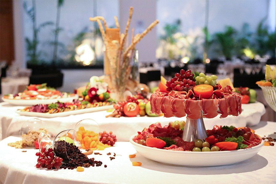 Elegante mesa de buffet com variadas travessas de frutas e sobremesas em um ambiente luminoso de banquete.