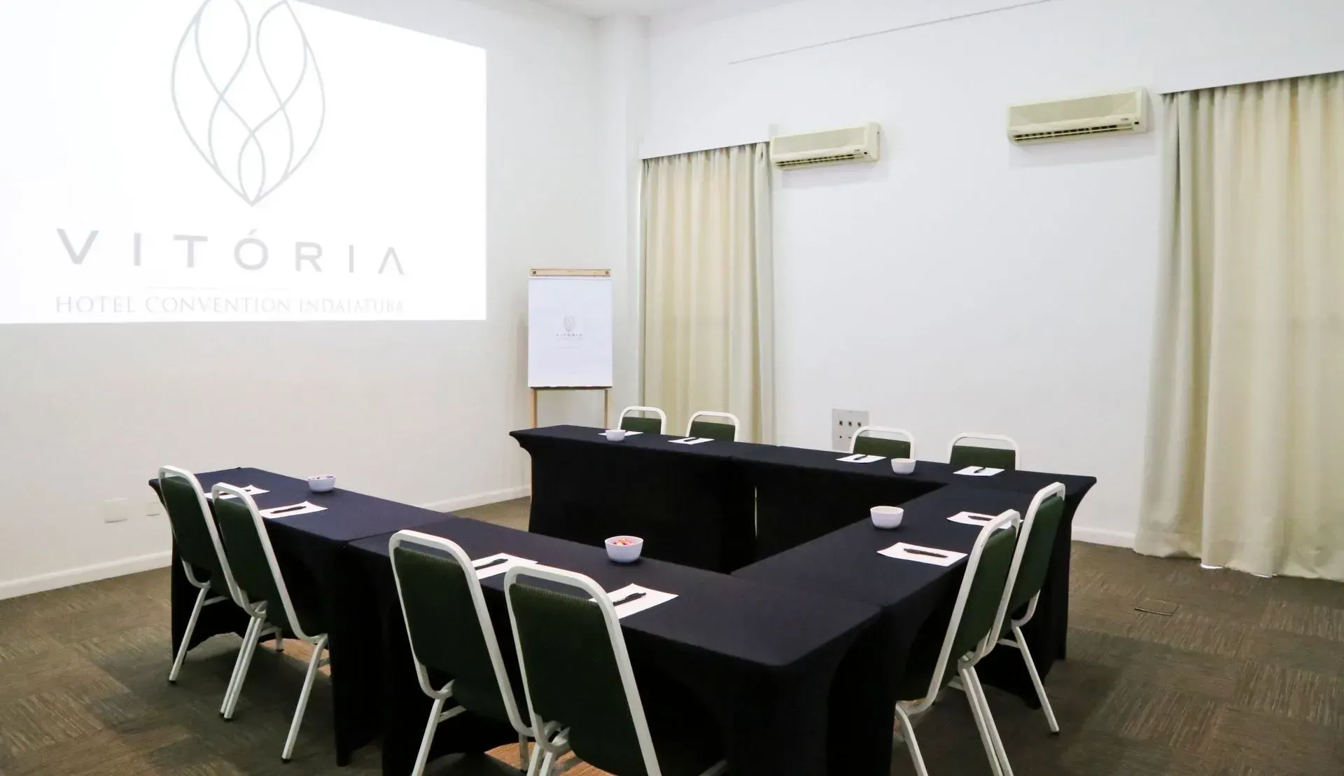 Uma sala de conferências com mesas e cadeiras em formato de U