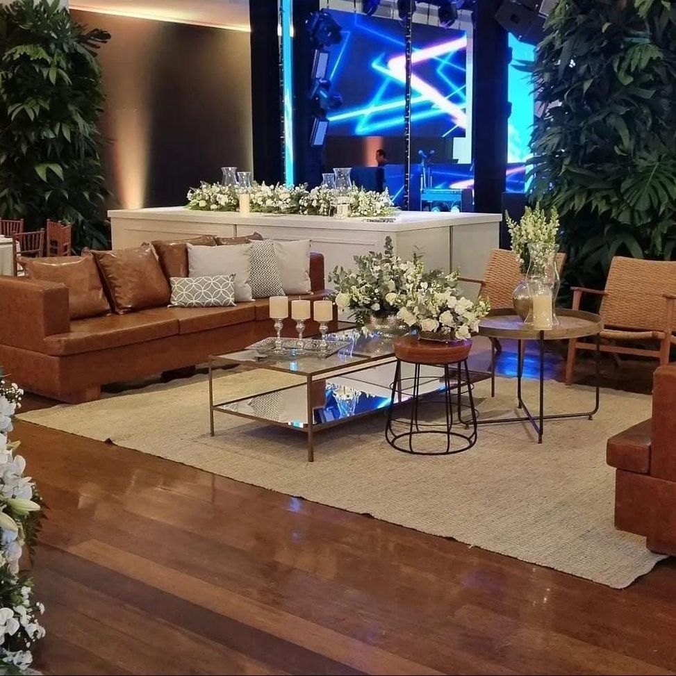 Sala de estar elegante com sofá de couro, mesa de centro de vidro, flores e luzes da cidade visíveis através de grandes janelas.