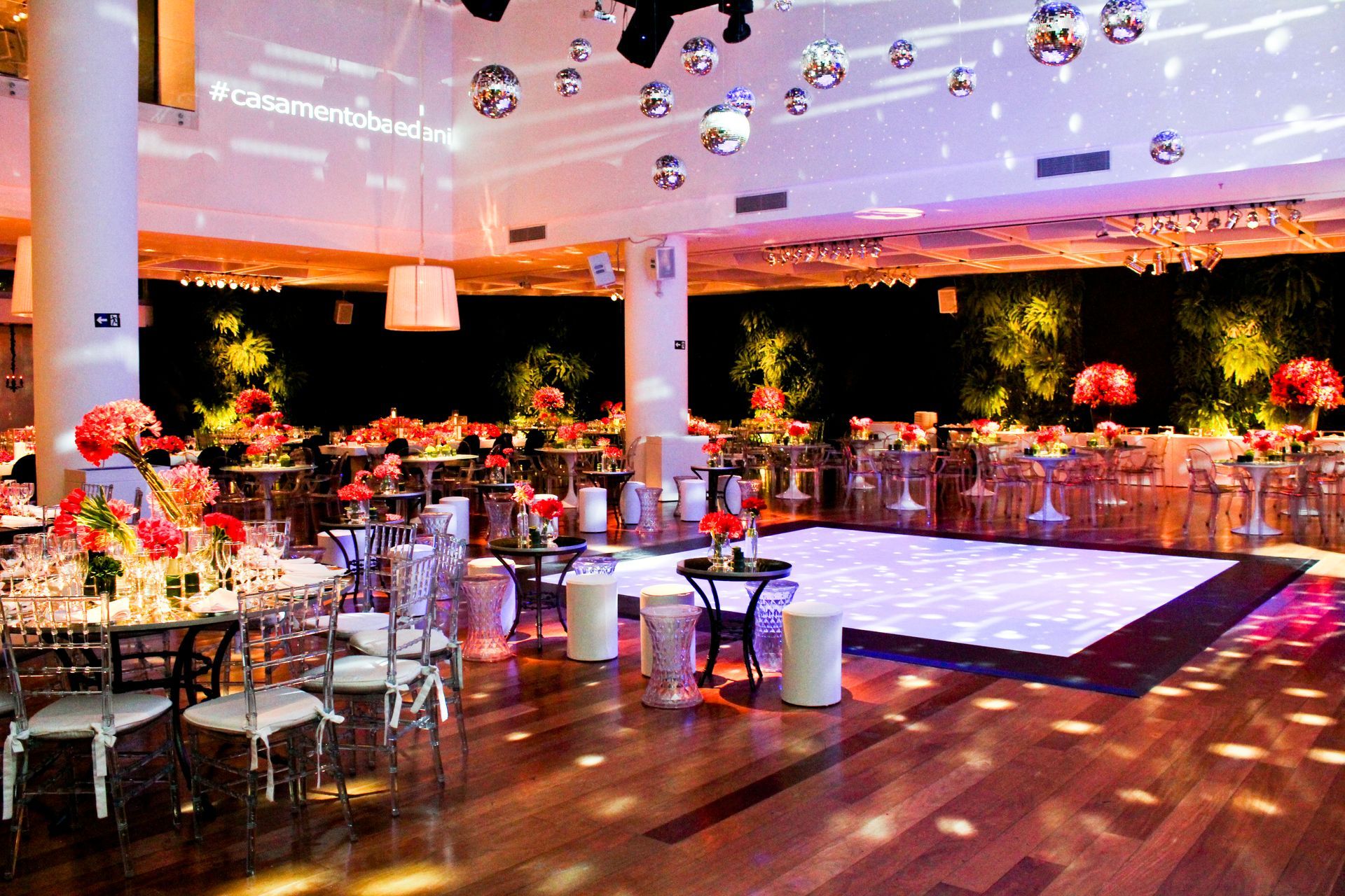 Salão de banquetes elegante com mesas redondas, pista de dança branca e iluminação aconchegante em tons de roxo.