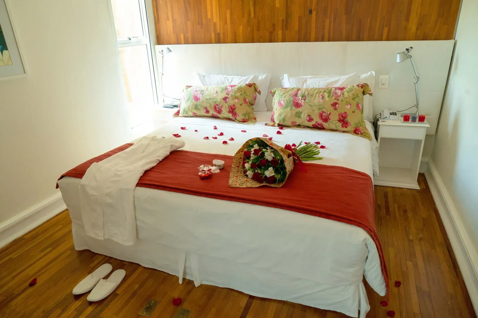 Uma cama com pétalas de rosa e buquê.