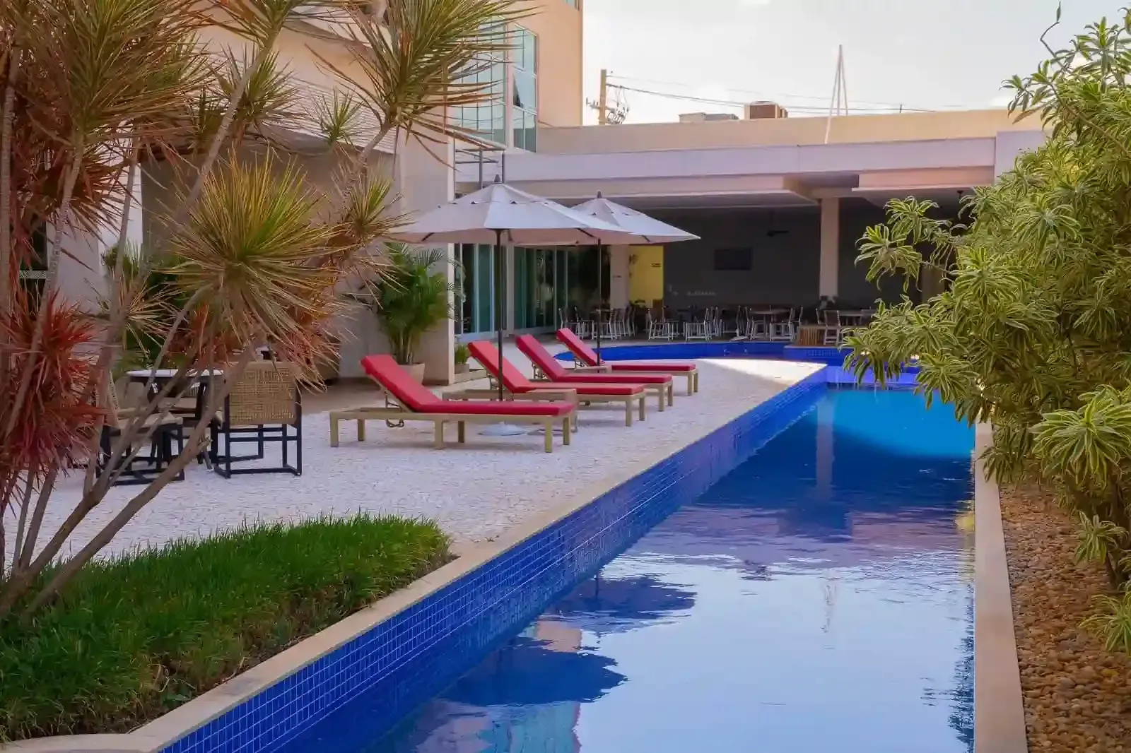 Cena à beira da piscina com espreguiçadeiras, guarda-sóis e água azul.