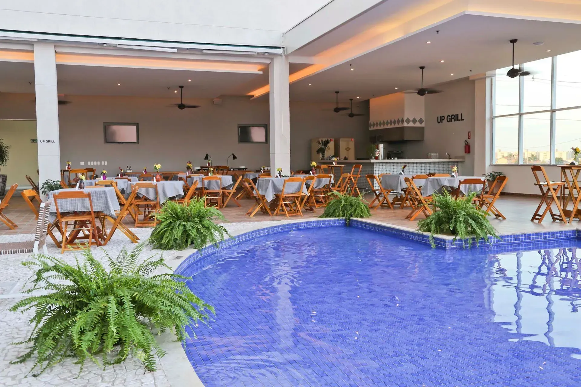 Um restaurante com mesas e cadeiras ao lado de uma piscina.