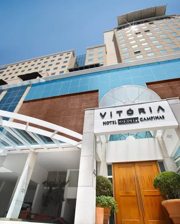 Exterior do Hotel Vitória Augusta Campinas com placa e portas de madeira. Prédio alto com detalhes em azul.