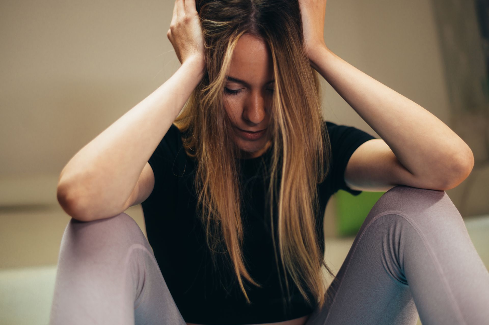 Person sitting with head in hands, looking distressed indoors.