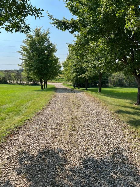 Gravel path through a sunny green park with trees and blue sky
