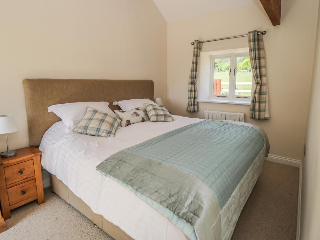 Bedroom with a bed, nightstand, and window with curtains; light colors and simple decor.