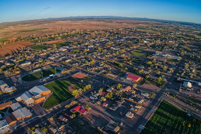 Aerial view of a town in a desert landscape with buildings, trees, and a large roundabout.