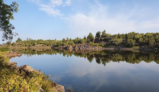 A boat on a lake with people, with a background of trees and a cliff face.