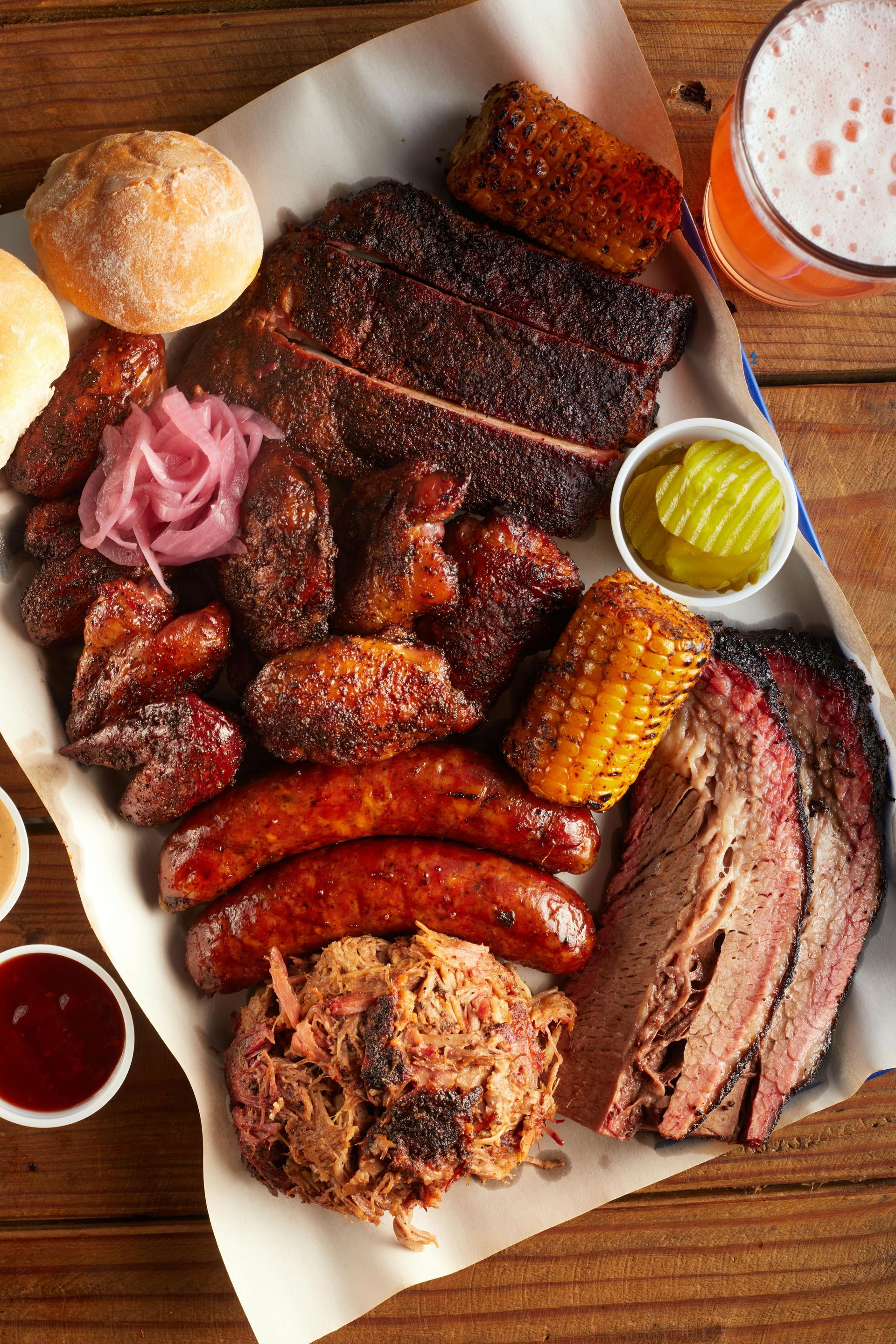 Barbecue platter with various meats, sides, and a beer.