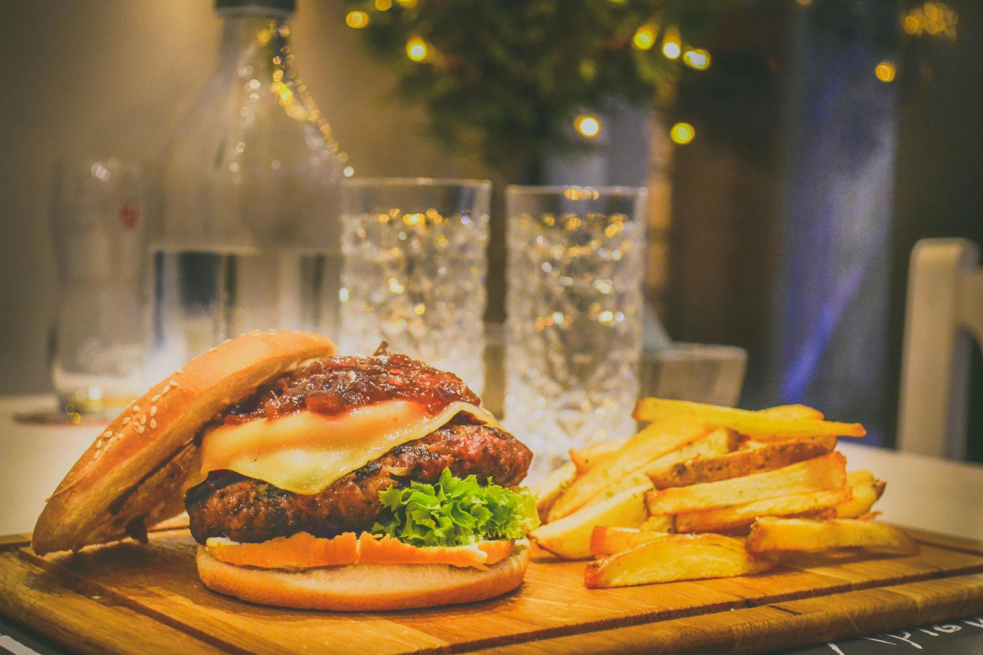 Steak and potato wedges on a wooden board with a small bowl of sauce.