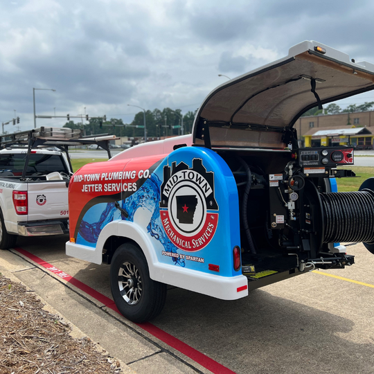 Blue-and-red emergency response trailer with open canopy and hose reels parked beside a white pickup in a lot