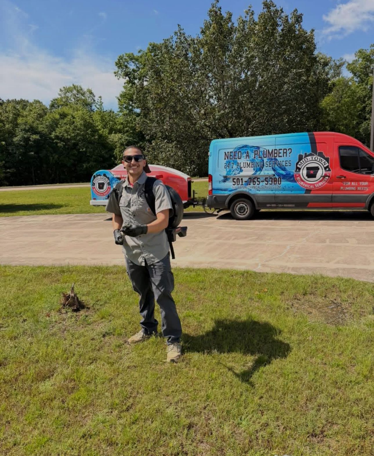 Person standing on grass in front of colorful vans under a sunny blue sky.