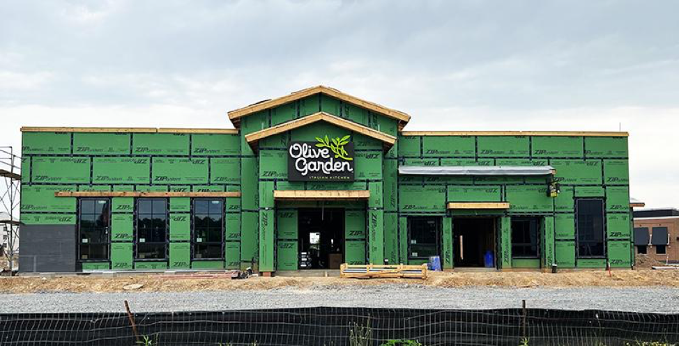 Green storefront with a central entrance and gold sign on a cloudy day