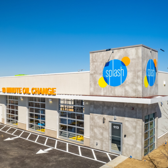 Exterior of a Splash car wash building with blue and yellow signage under a clear sky