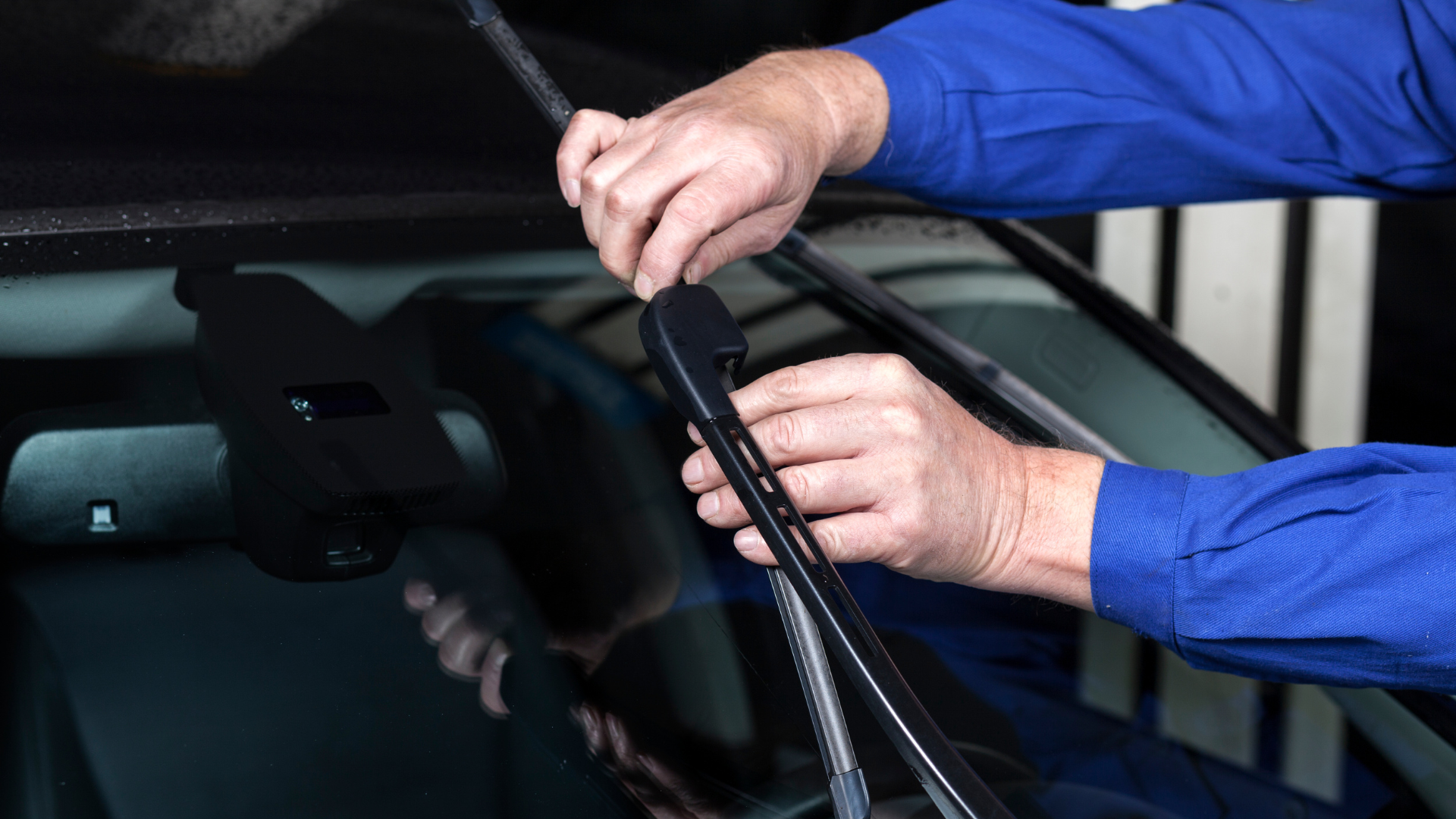 A man is fixing a windshield wiper on a car.