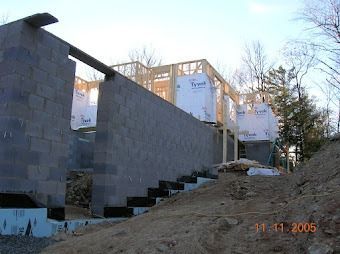 Unfinished cinder block building under construction with stairs and wooden framing in a yard