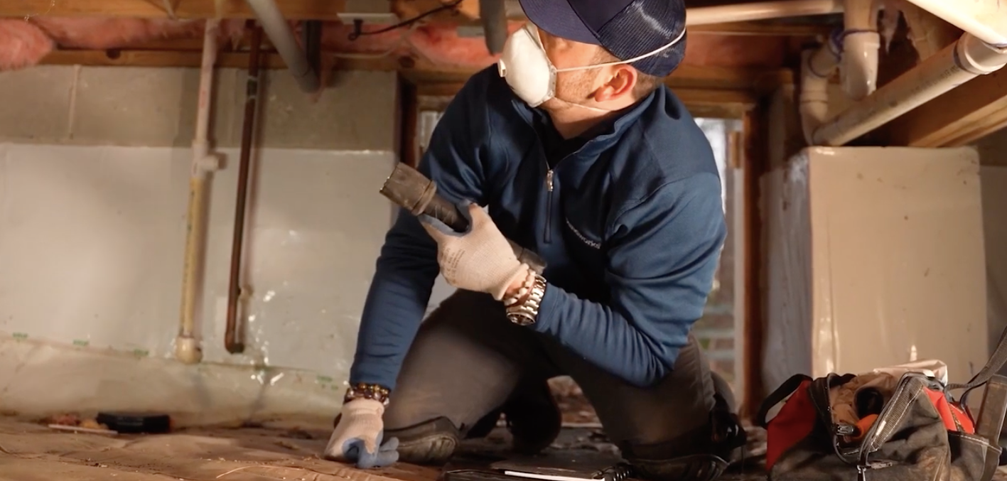 Foundation repair specialist inspecting the foundation beneath a home in a crawl space