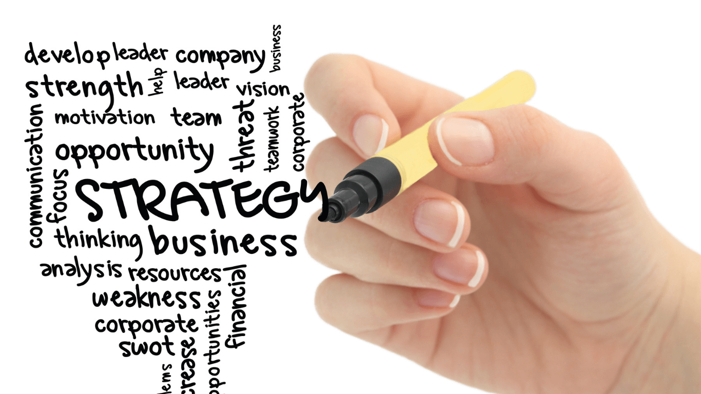 A hand is writing the word strategy with a marker