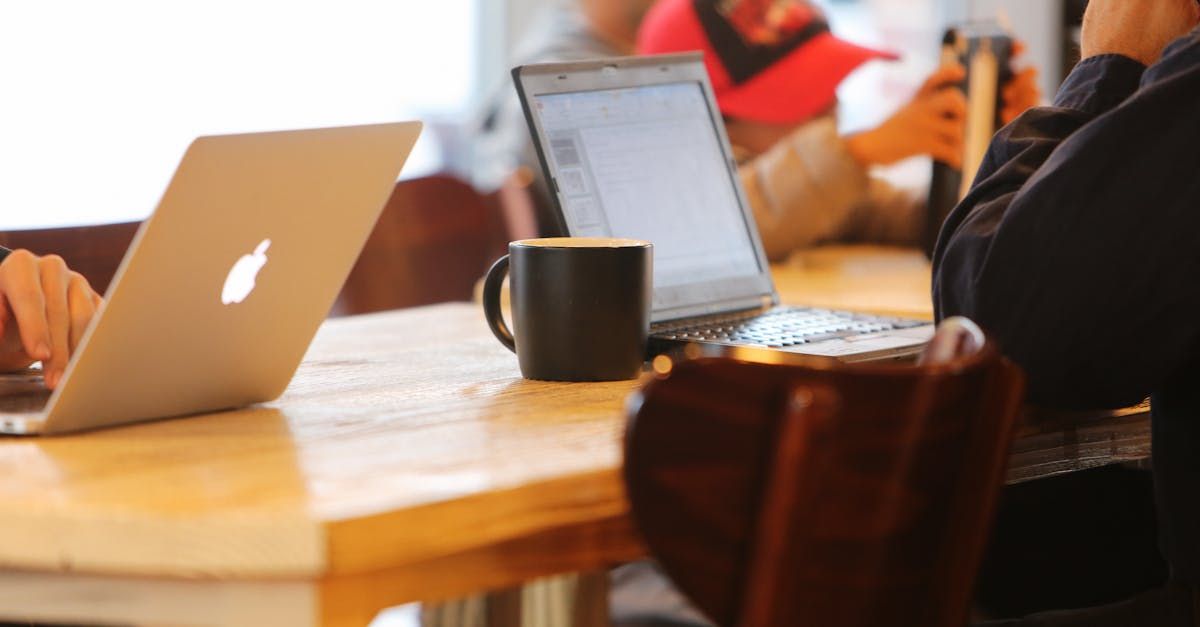 A group of people are sitting at a table with laptops and a cup of coffee.