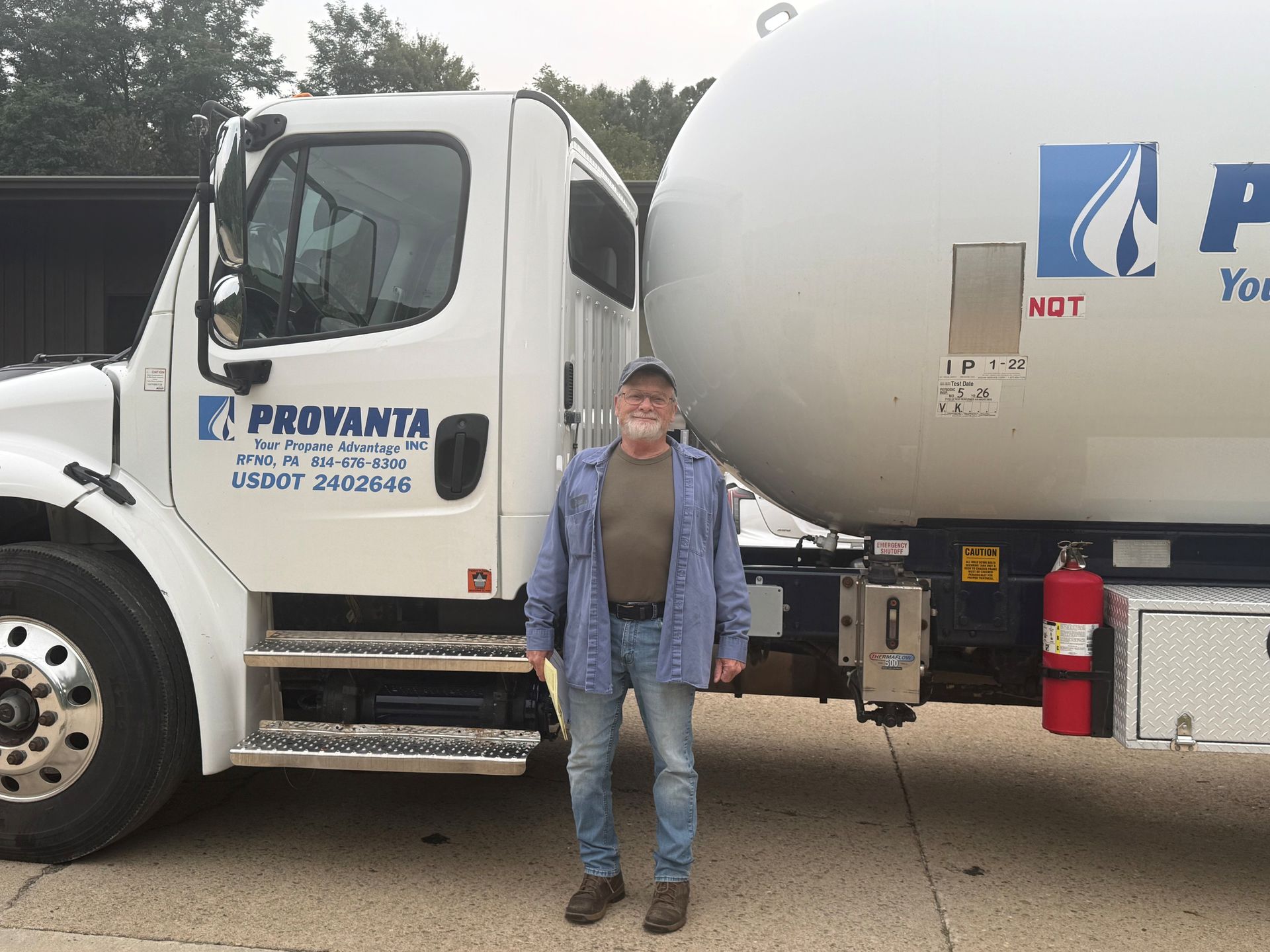 Man standing beside a white PROVANTA truck, wearing blue shirt, suspenders, jeans, and cap.