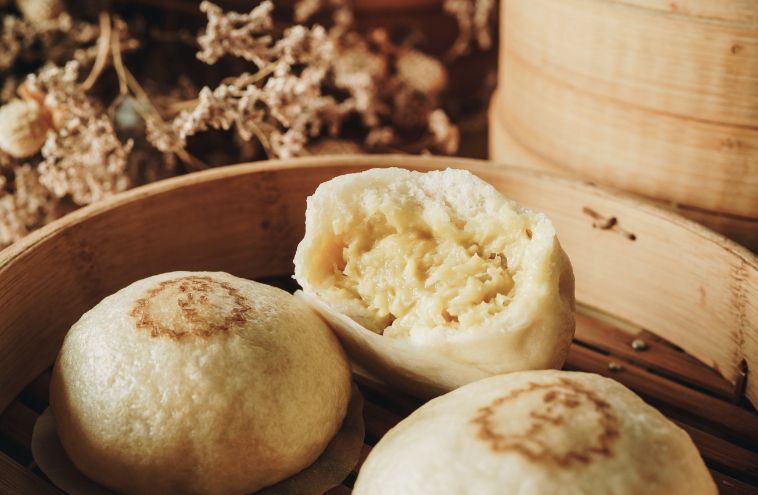 A close up of three dumplings in a bamboo steamer.