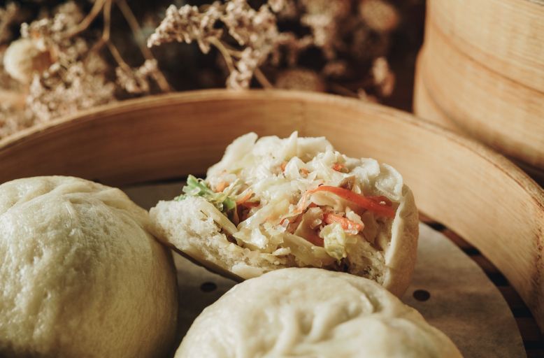 A close up of a sandwich in a bamboo steamer.