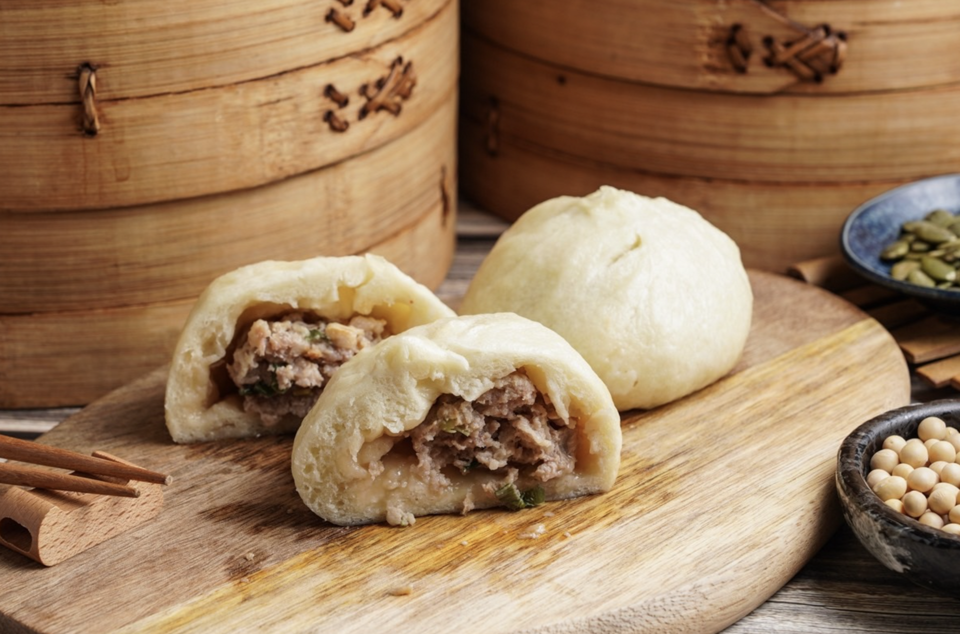Three dumplings are sitting on a wooden cutting board.