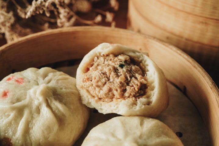 A close up of three dumplings in a bamboo steamer.