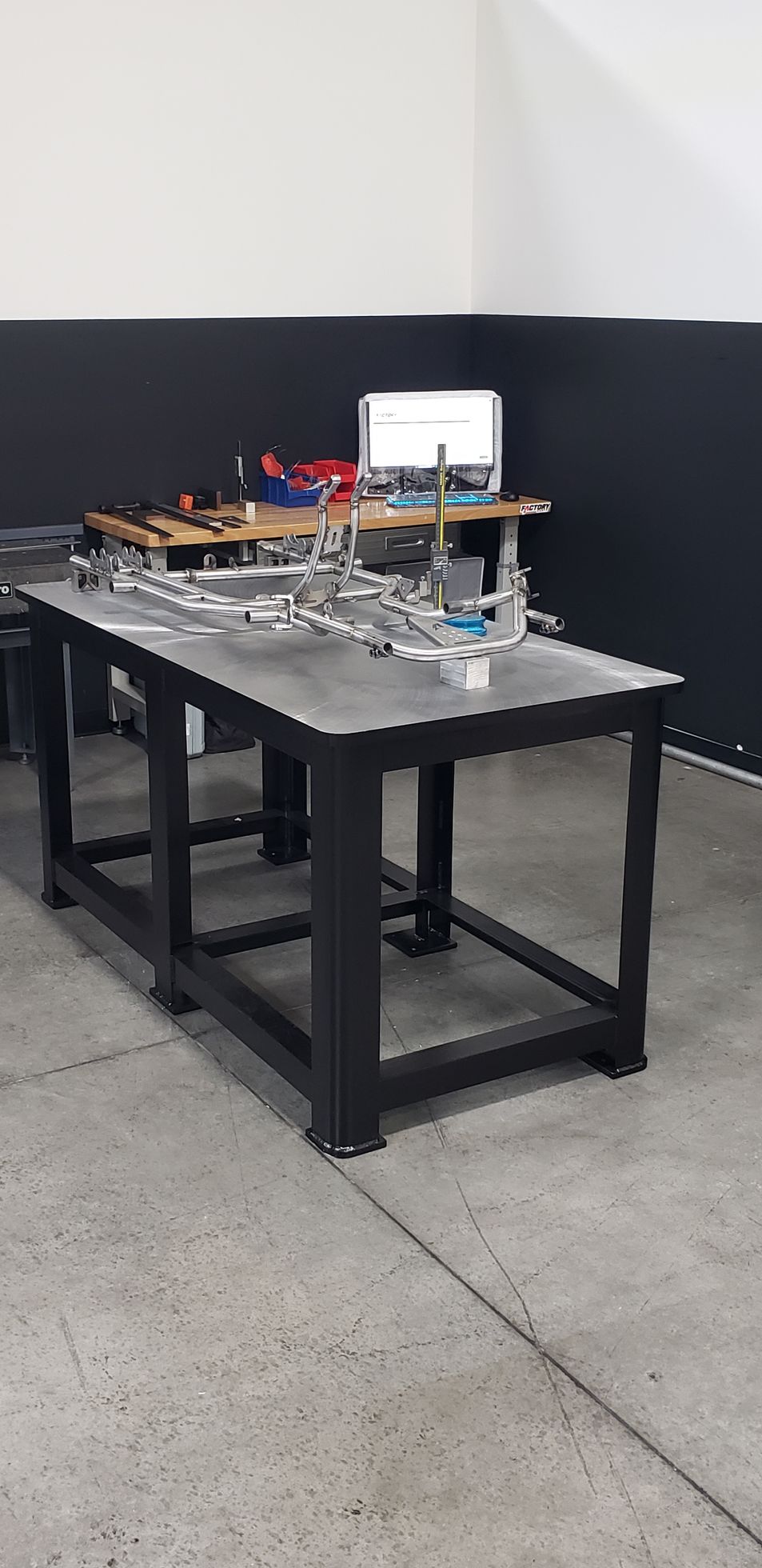 Mechanical device on a black table in a plain indoor room, with wires, components, and a small display.