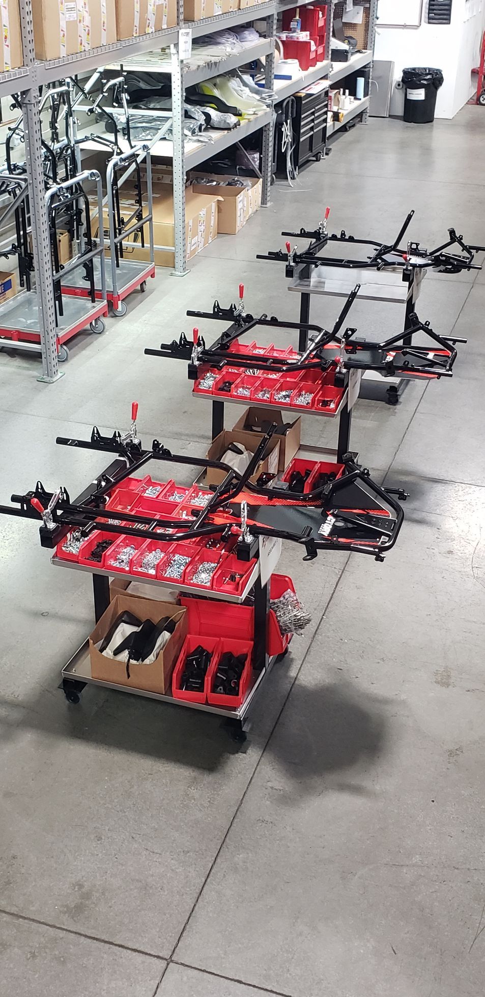 Red drone-like robot on a workshop floor beside shelves and tools