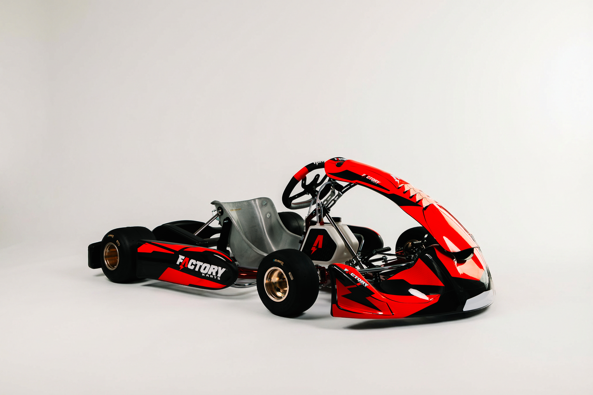 Red and black race car on a white background, shown in side view with exposed cockpit and rear wing