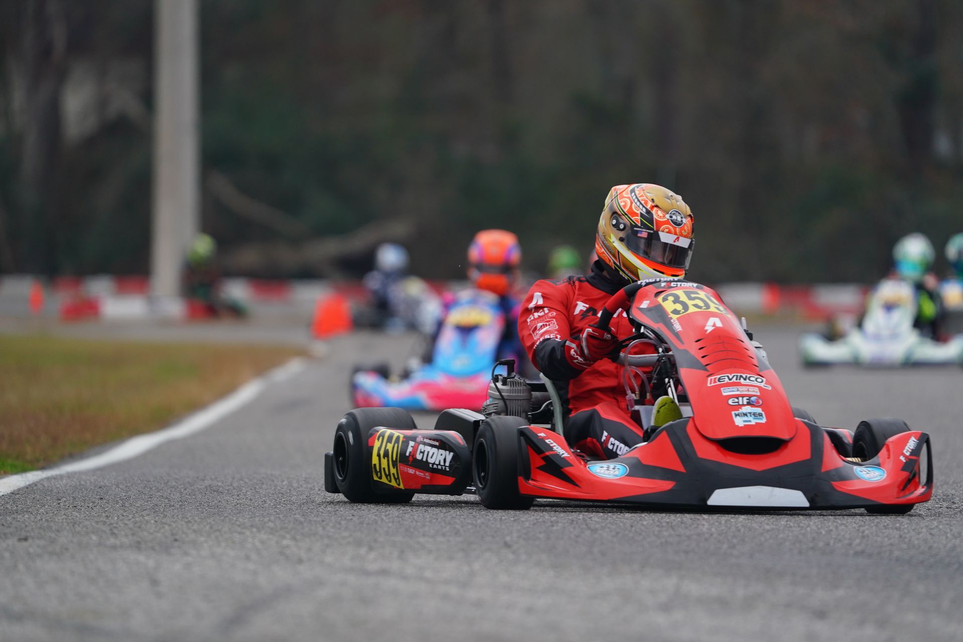 Red go-kart racing on a track with other drivers blurred in the background
