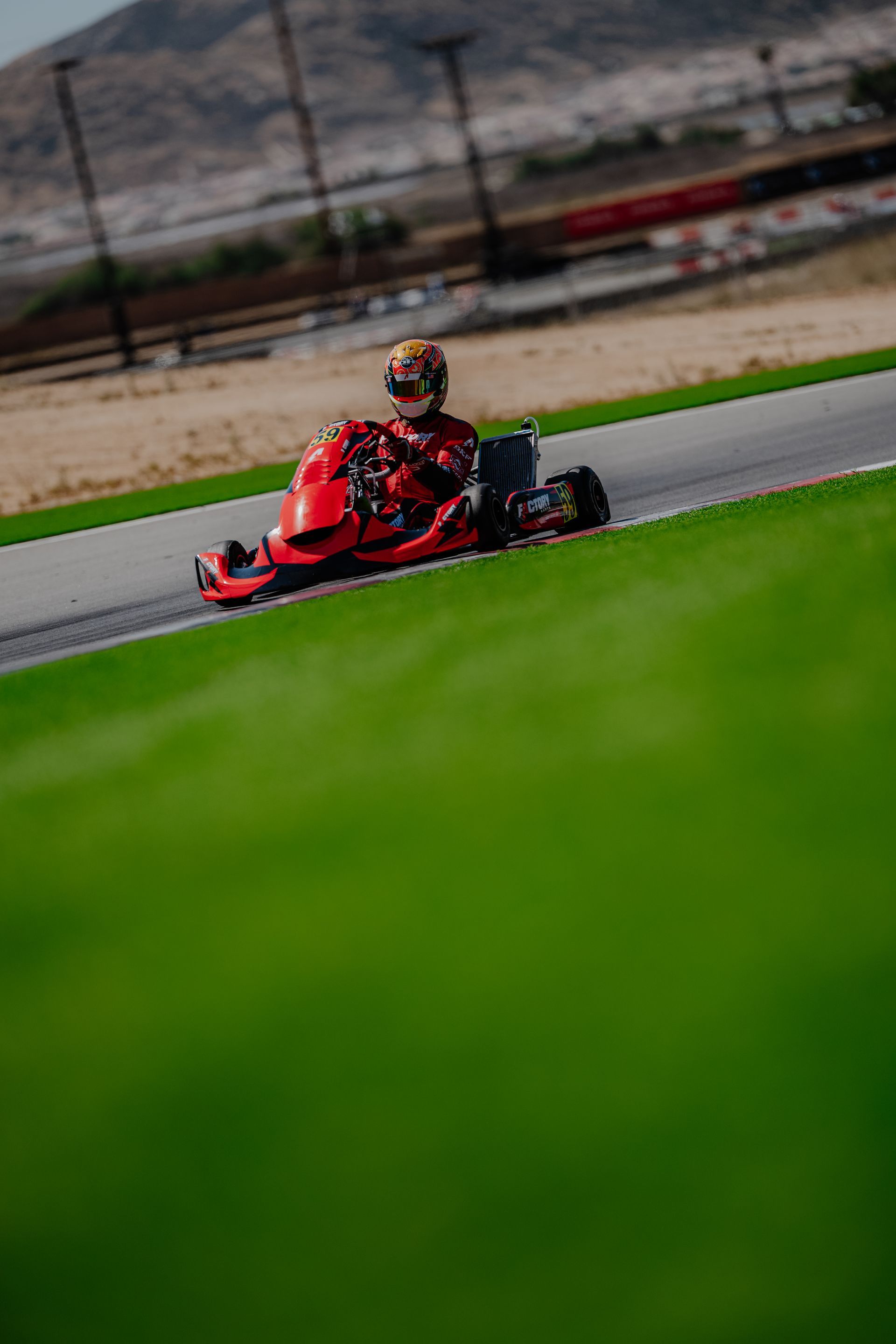 Go-kart racers speeding around a track, with a red kart leading a blue kart in the foreground