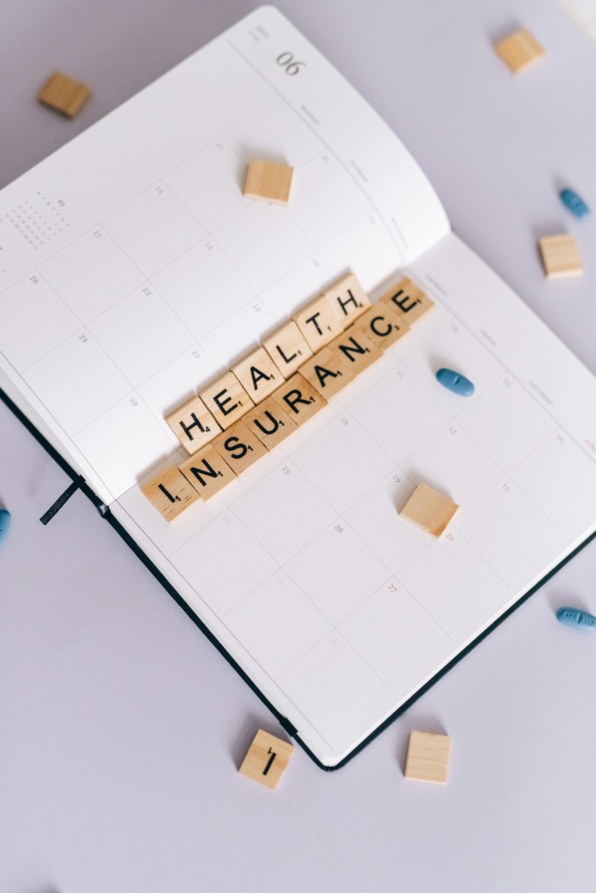 A notebook with scrabble tiles that say health insurance